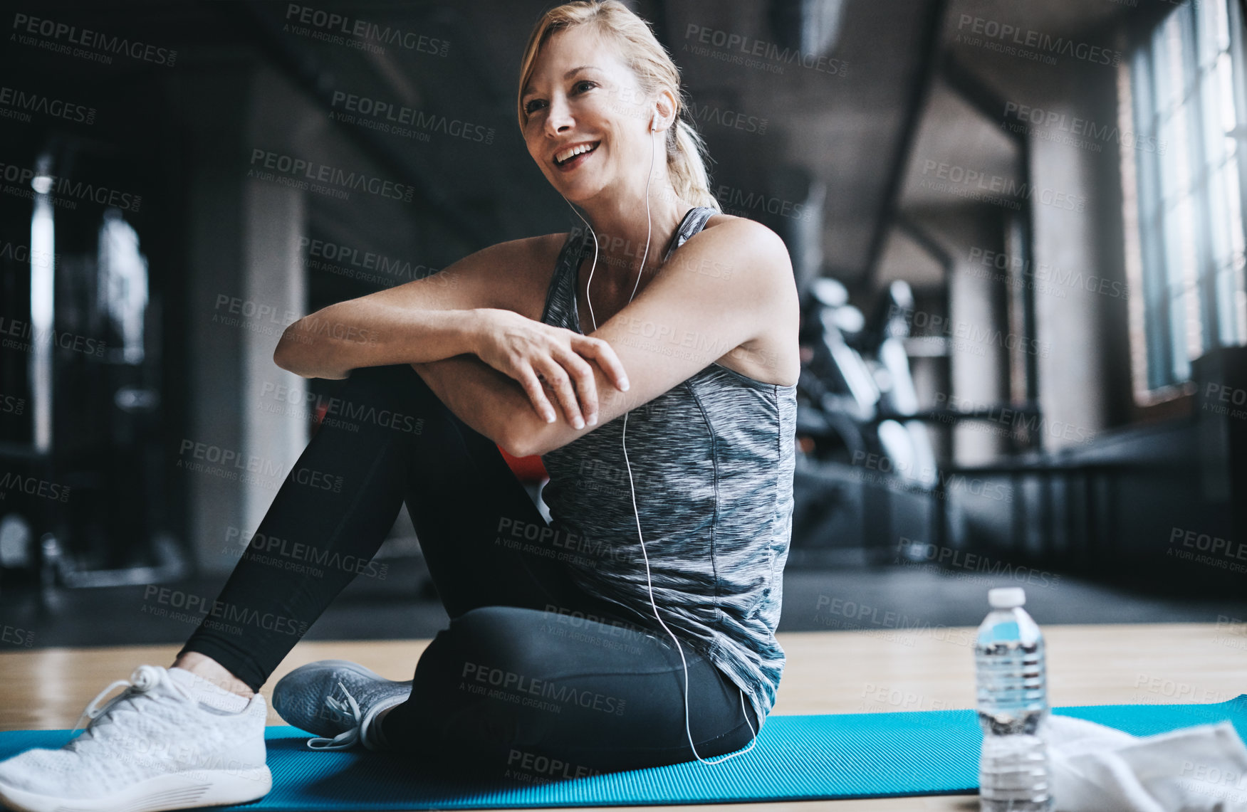 Buy stock photo Full length shot of an attractive young woman listening to music while working out in the gym