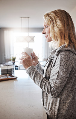 Buy stock photo Shot of a mature woman relaxing at home with a cup of coffee