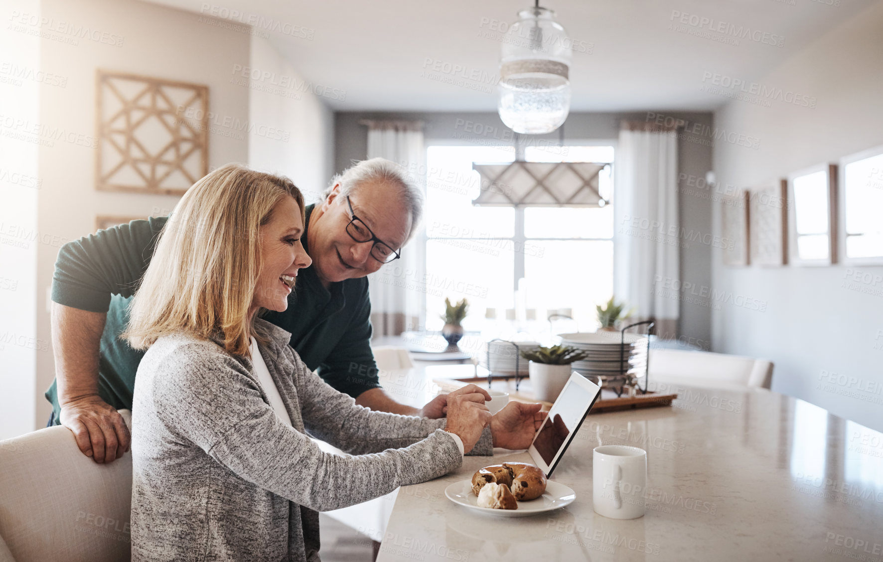 Buy stock photo Shot of a mature woman using a digital tablet during a relaxed morning at home