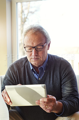 Buy stock photo Cropped shot of a senior man using a tablet at home