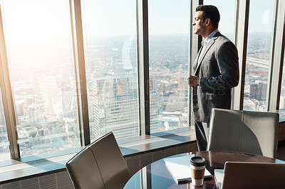 Buy stock photo Shot of a young businessman looking out the window in an office