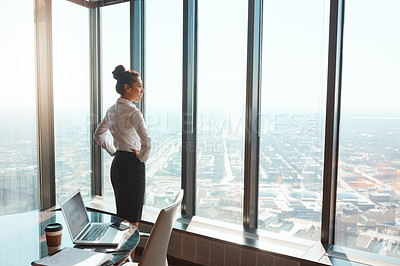Buy stock photo Rearview shot of an attractive young businesswoman standing with her hands on her hips in the office