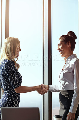 Buy stock photo Cropped shot of two young businesswoman shaking hands in their office
