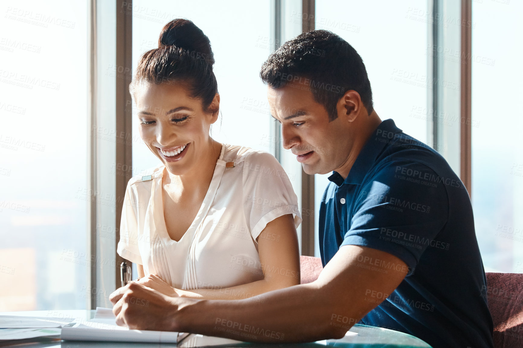 Buy stock photo Shot of a young man and woman going through paperwork together in an office