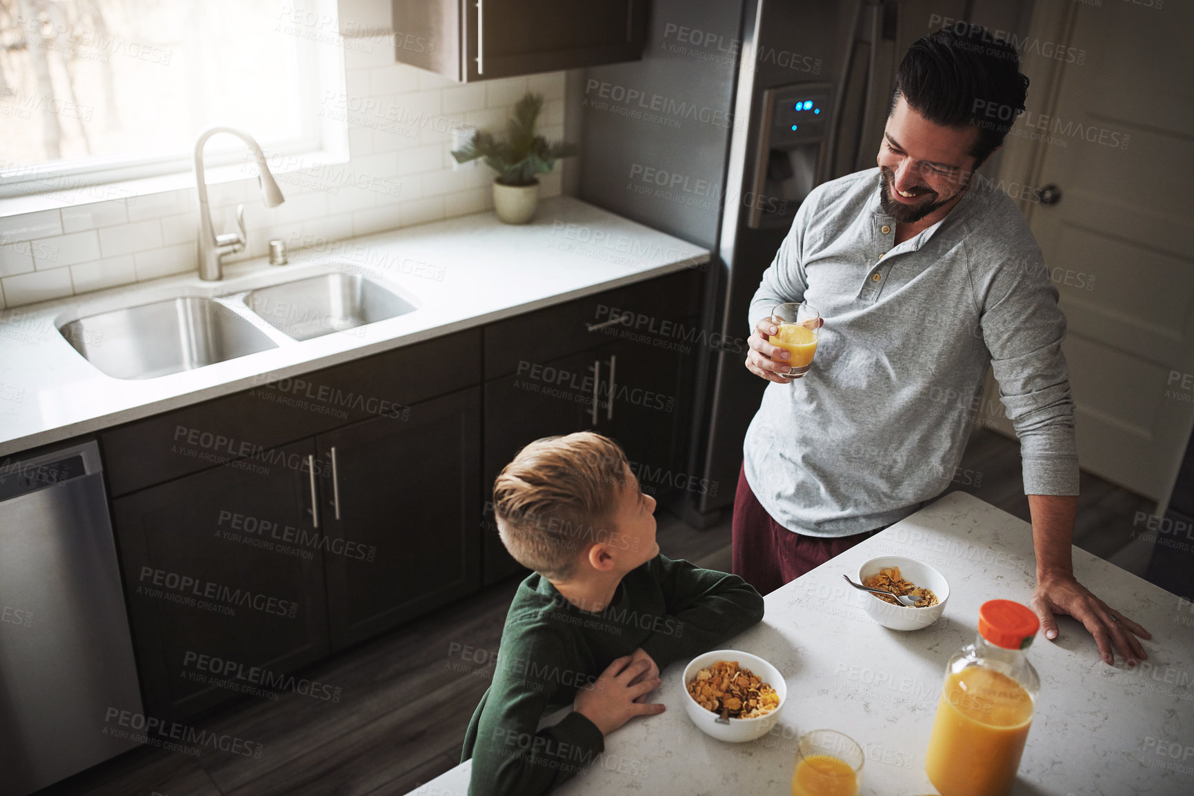Buy stock photo High angle shot of a young boy and his father having breakfast in the kitchen