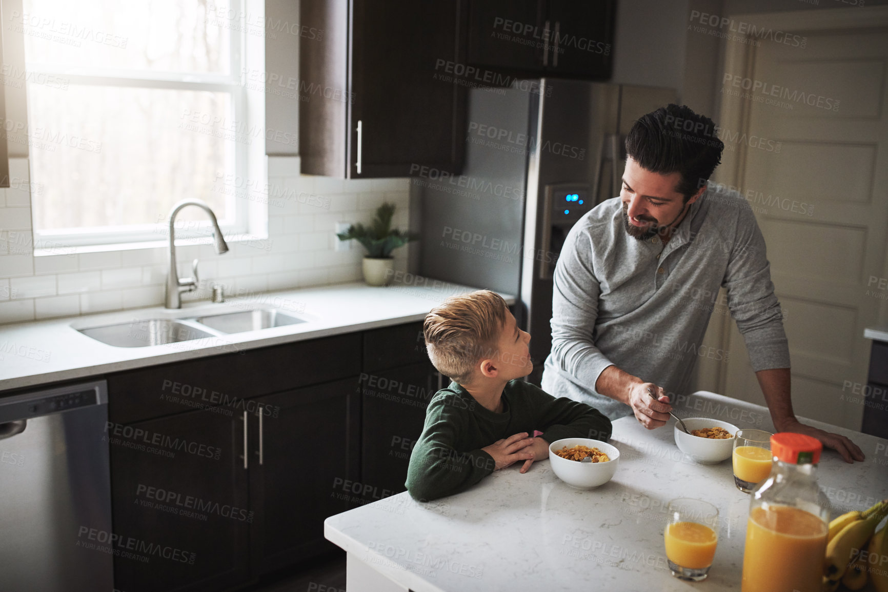 Buy stock photo High angle shot of a young boy and his father having breakfast in the kitchen
