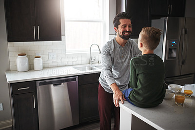 Buy stock photo High angle shot of a handsome young man talking to his son while standing in the kitchen