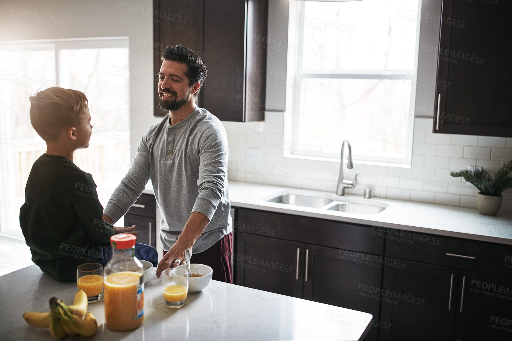 Buy stock photo High angle shot of a handsome young man talking to his son while having breakfast
 in the kitchen