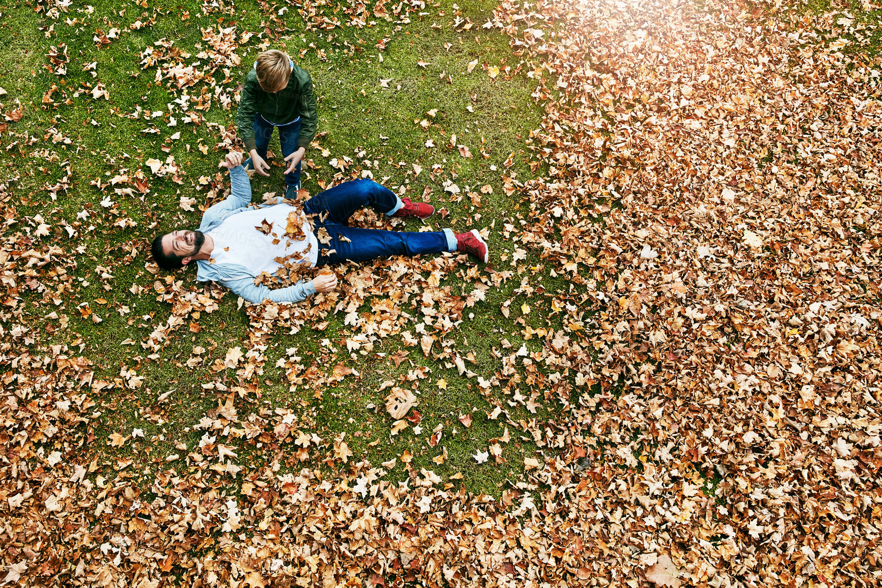 Buy stock photo Shot of a father and his little son playing in the autumn leaves outdoors