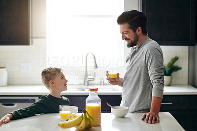 Buy stock photo Cropped shot of a handsome young man talking to his son while having breakfast
 in the kitchen