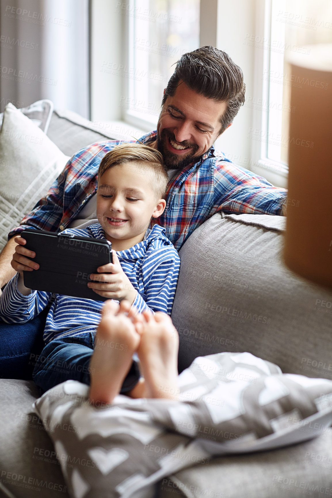 Buy stock photo Shot of a little boy using a digital tablet with his father at home