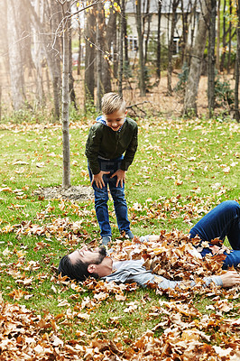 Buy stock photo Shot of a father and his little son playing in the autumn leaves outdoors