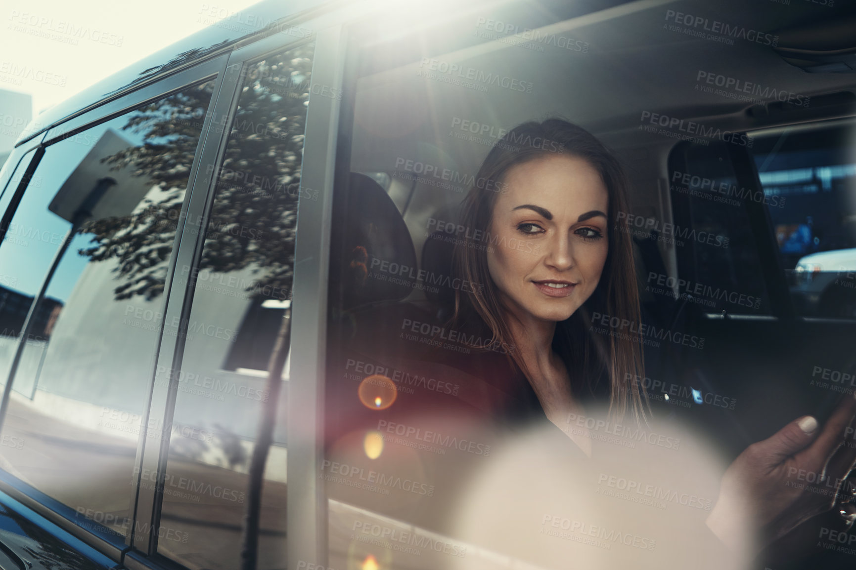 Buy stock photo Shot of a young businesswoman using a mobile phone while traveling in a car