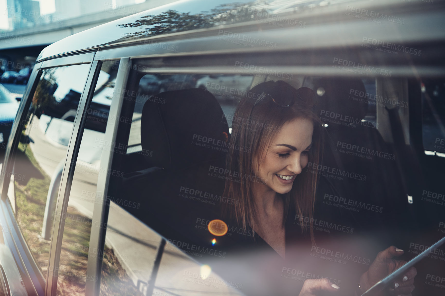 Buy stock photo Shot of a young businesswoman using a digital tablet while traveling in a car
