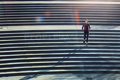 Buy stock photo High angle shot of an attractive young sportswoman running up and down stairs outside