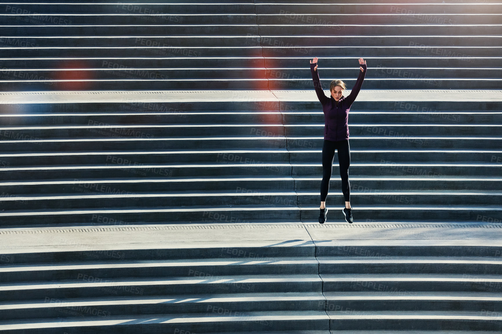 Buy stock photo Full length shot of an attractive young sportswoman doing jumping jacks on outside stairs