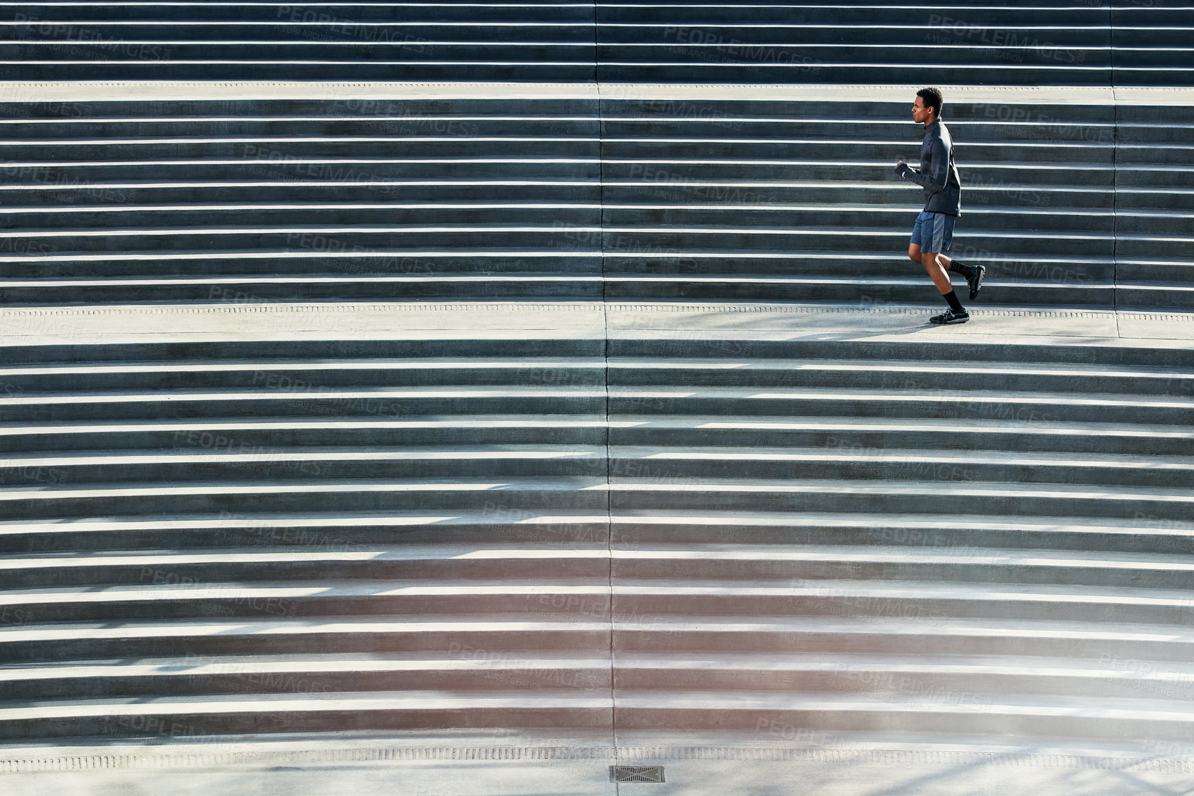 Buy stock photo Full length shot of a handsome young sportsman running up and down stairs outside