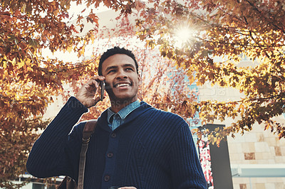 Buy stock photo Shot of a young businessman using a mobile phone while walking outdoors