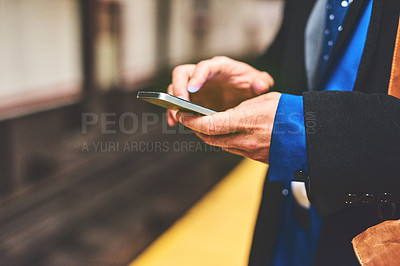 Buy stock photo Shot of an unrecognizable man texting on his phone while waiting for a train to get to work in the morning