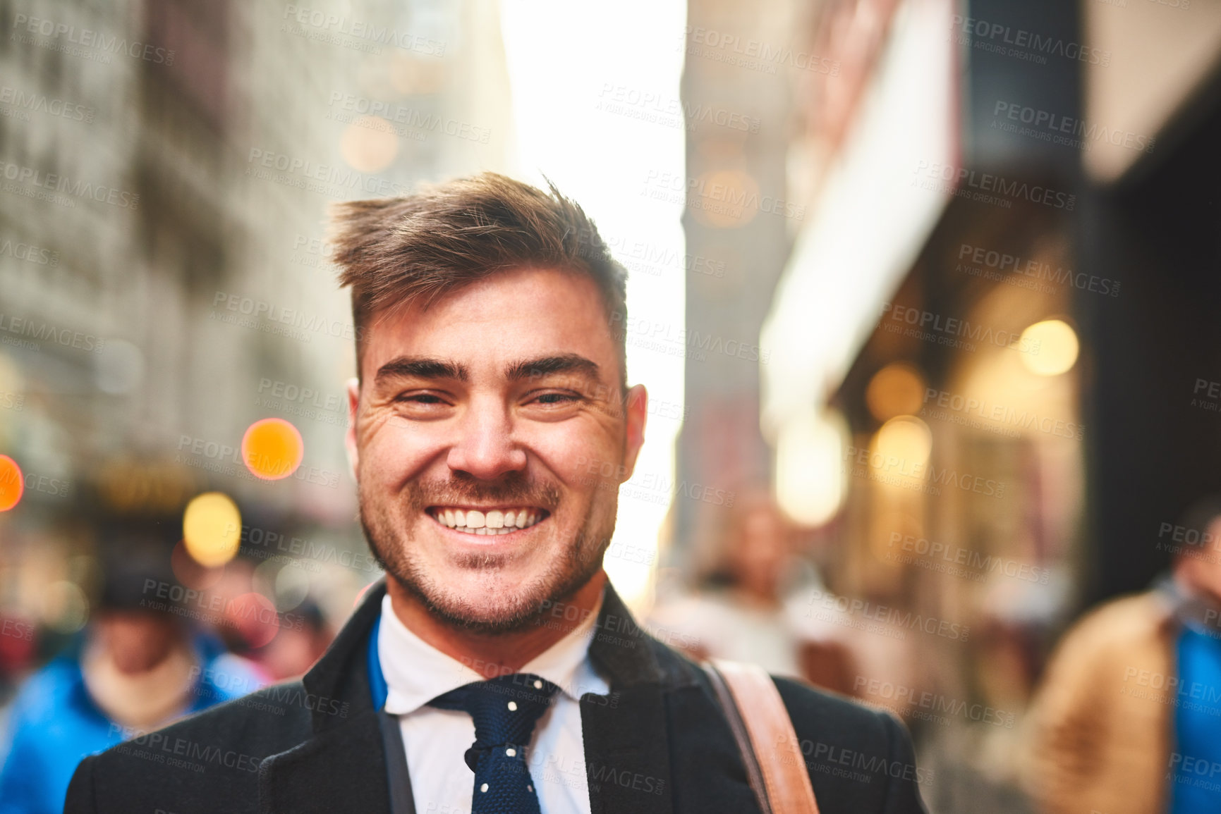 Buy stock photo Portrait of a cheerful young businessman standing in the middle of the busy streets of the city during morning hours