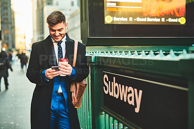Buy stock photo Shot of a cheerful young man texting on his cellphone while standing in the busy streets of the city during the day