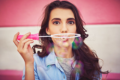 Buy stock photo Cropped shot of a beautiful young woman blowing bubbles outside