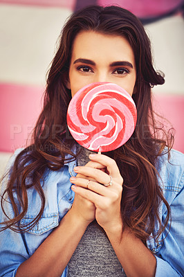 Buy stock photo Portrait of a beautiful young woman holding candy against a wall outside