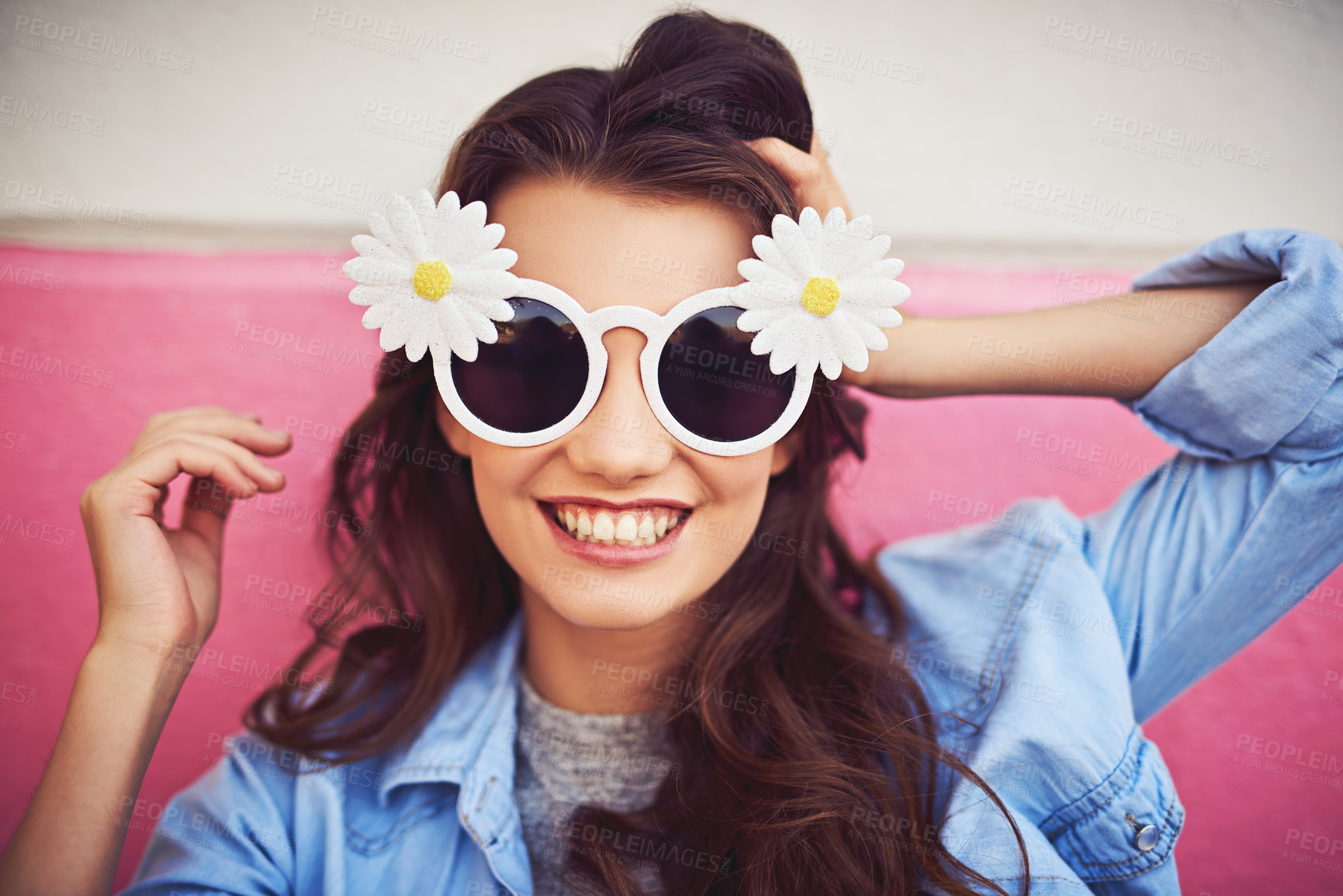 Buy stock photo Cropped shot of a beautiful young woman wearing novelty sunglasses and posing against a wall outside