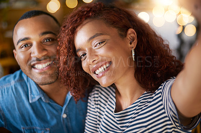 Buy stock photo Cropped shot of an affectionate young couple taking selfies while sitting in a coffee shop