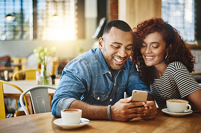 Buy stock photo Cropped shot of an affectionate young couple looking at a cellphone while sitting in a coffee shop