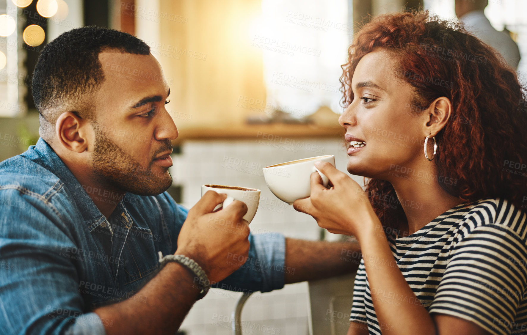 Buy stock photo Cropped shot of a young couple talking while sitting in a coffee shop