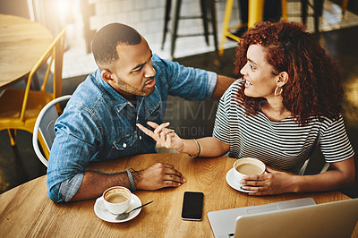 Buy stock photo High angle shot of a young couple working on a laptop while sitting in a coffee shop