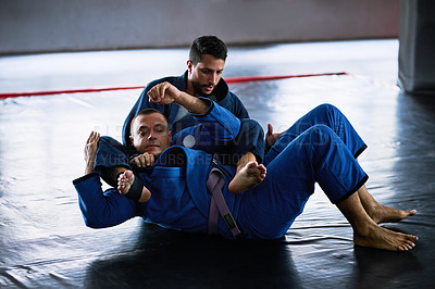 Buy stock photo Full length shot of two young male athletes sparring on the floor of their dojo