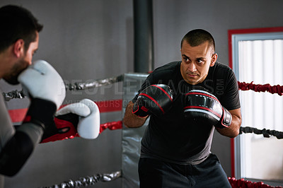 Buy stock photo Cropped shot of two young male athletes sparring in a boxing ring