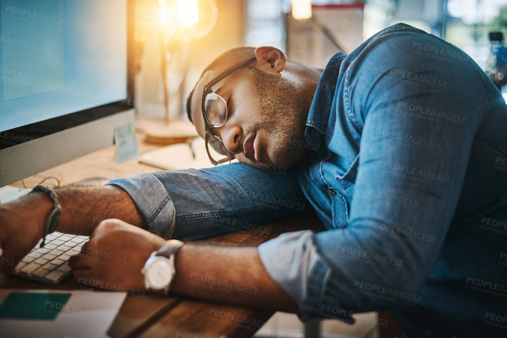 Buy stock photo Shot of an exhausted young businessman sleeping at his desk in a modern office