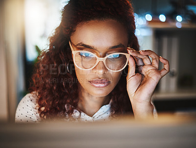 Buy stock photo Shot of a young businesswoman using a computer during a late night at work in a modern office