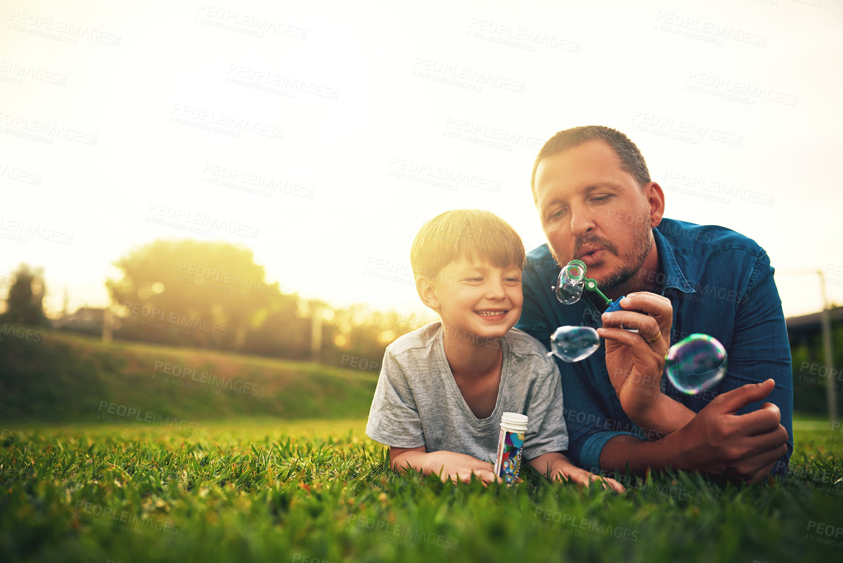 Buy stock photo Garden, family and father and boy with bubble for quality time, bonding and having fun together. Summer, parenthood and happy dad and child blowing bubbles in park for playing, happiness and relaxing