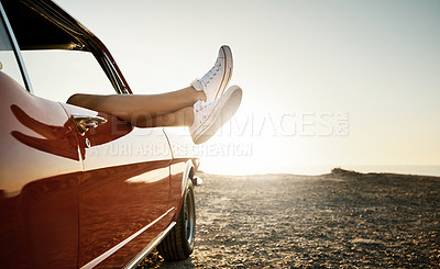 Buy stock photo Shot of an unrecognizable woman's legs sticking out the window of a car along the coast