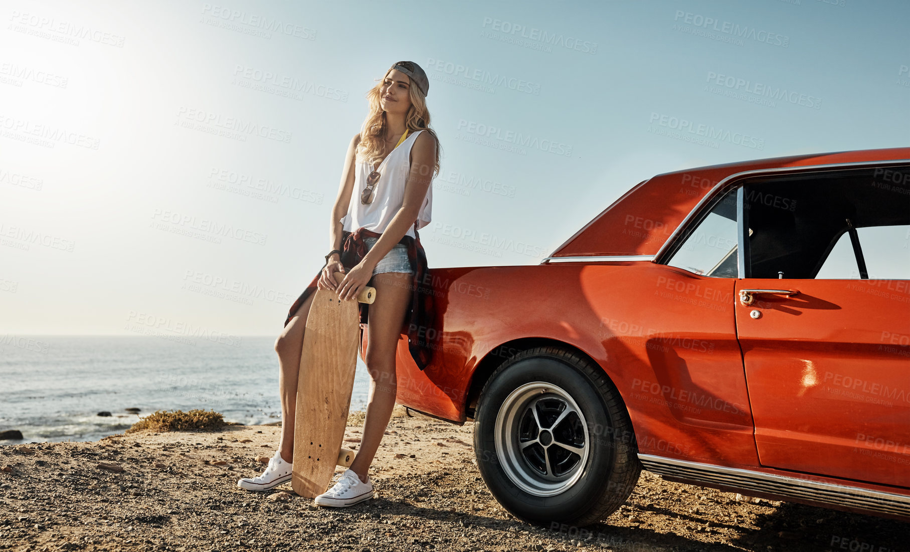 Buy stock photo Shot of an attractive young woman holding a skateboard while on a road trip