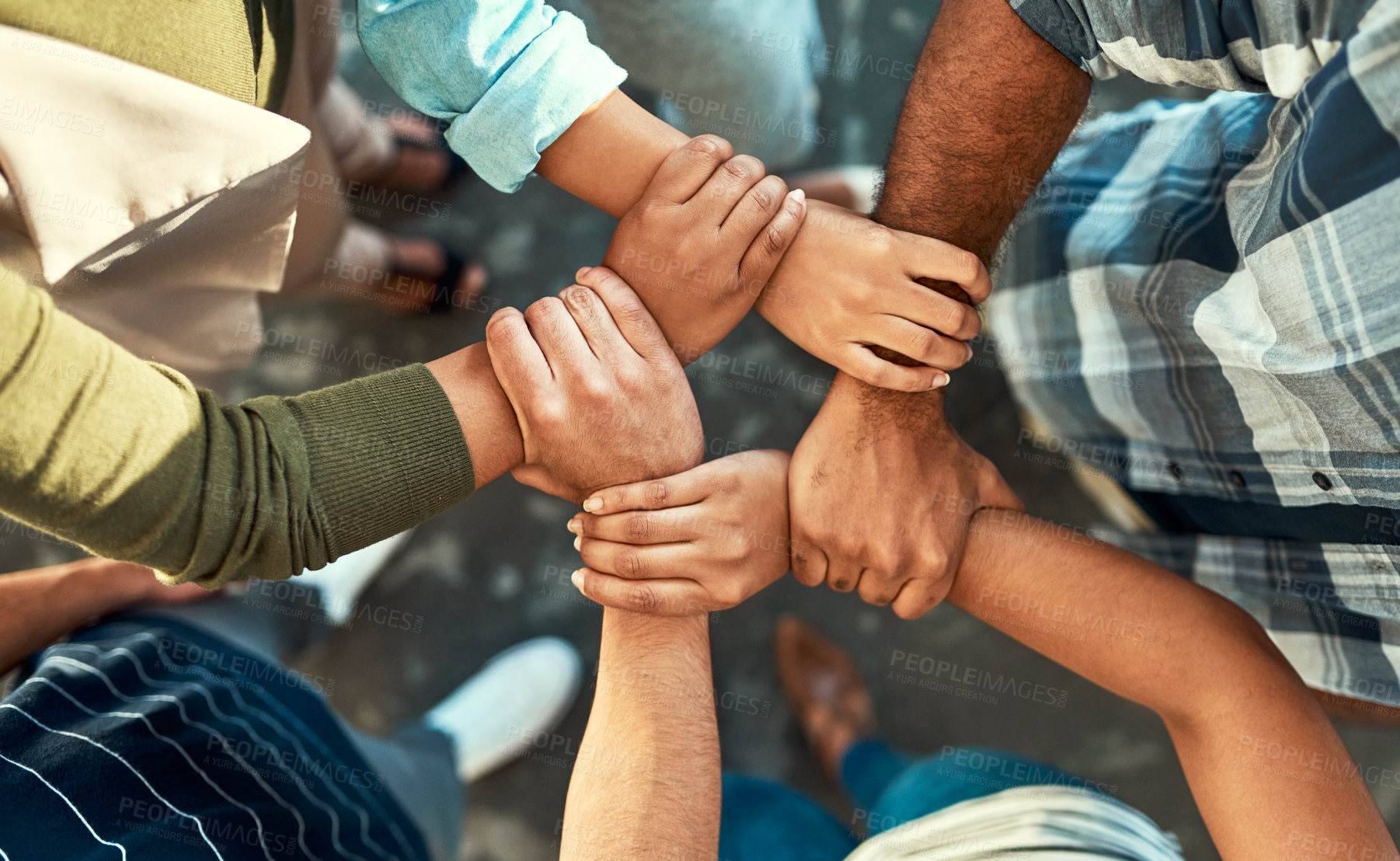 Buy stock photo High angle shot of a young group of work colleagues forming an unique huddle with their arms and hands while standing in the office at work