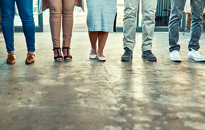 Buy stock photo Low angle shot of a group of unrecognizable work colleagues standing side by side in a straight line inside the office during the day