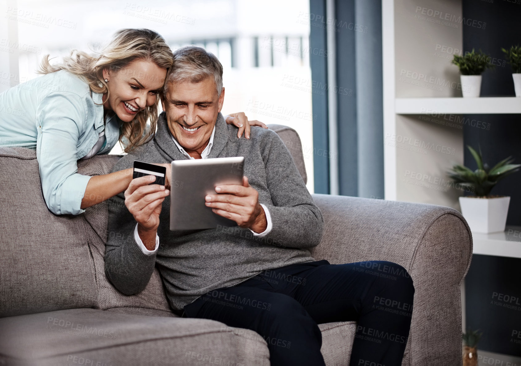 Buy stock photo Shot of a mature couple using a digital tablet and credit card to do online shopping at home