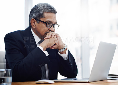Buy stock photo Shot of a mature businessman working on a laptop in an office