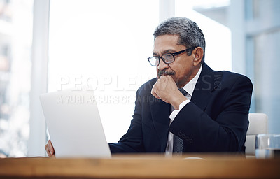 Buy stock photo Shot of a mature businessman working on a laptop in an office