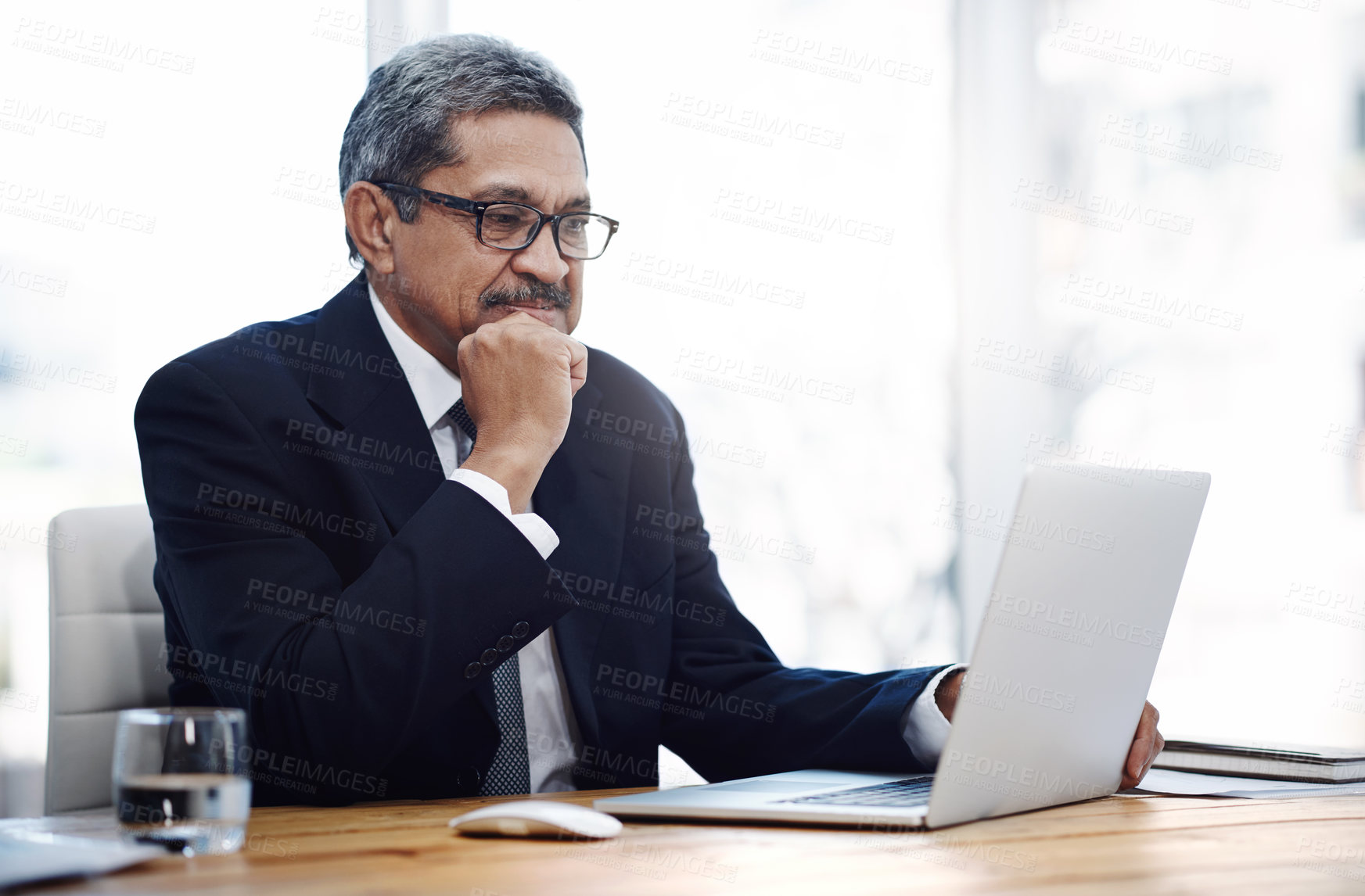 Buy stock photo Shot of a mature businessman working on a laptop in an office