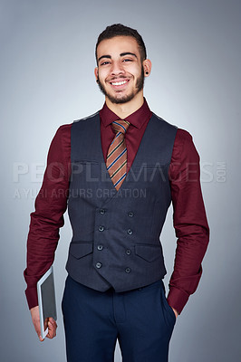 Buy stock photo Studio shot of a handsome young businessman holding a tablet against a grey background