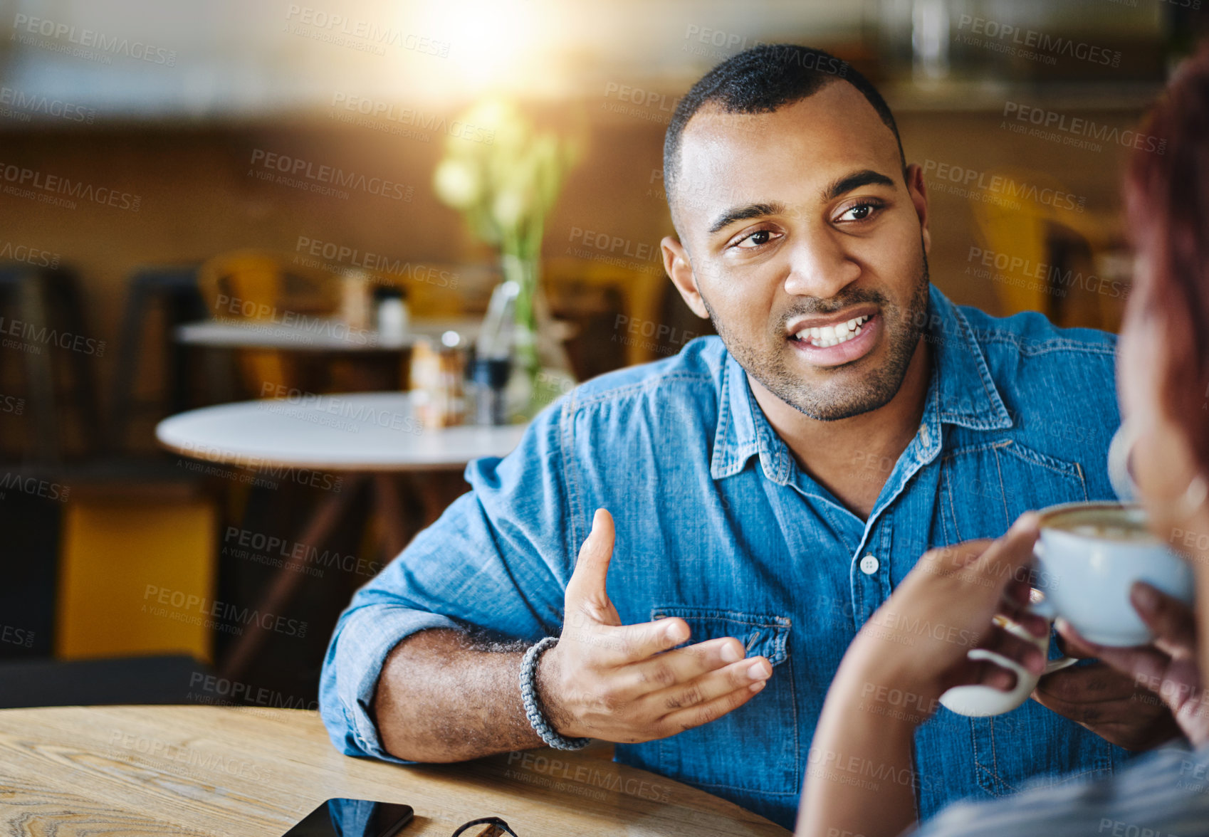 Buy stock photo Cropped shot of a handsome young man spending time with his girlfriend in a coffee shop