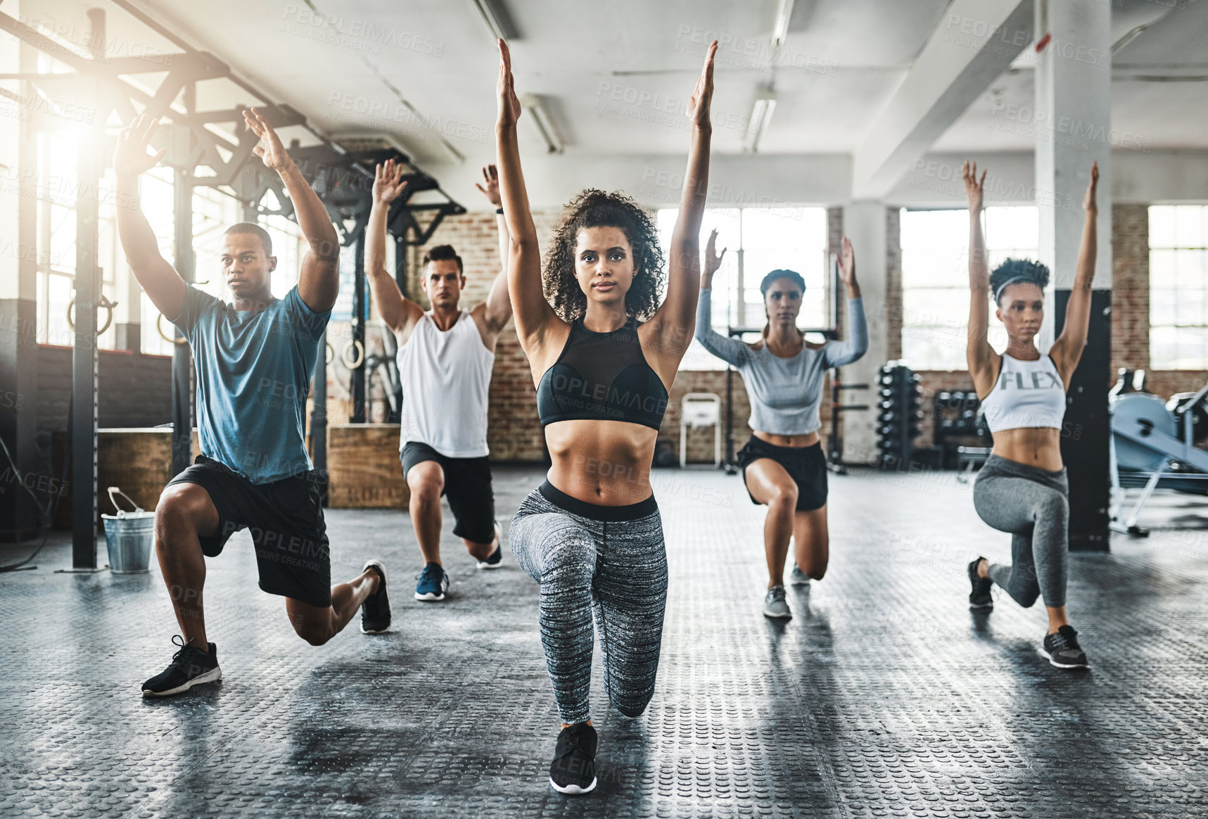 Buy stock photo Shot of a group of young people doing lunges together during their workout in a gym