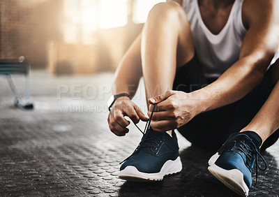 Buy stock photo Cropped shot of a man tying his shoelaces in a gym