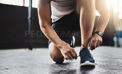 Buy stock photo Cropped shot of a man tying his shoelaces in a gym